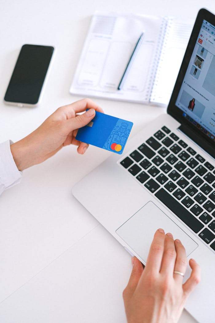 Person making an online purchase with a credit card on a laptop, showcasing modern ecommerce technology.